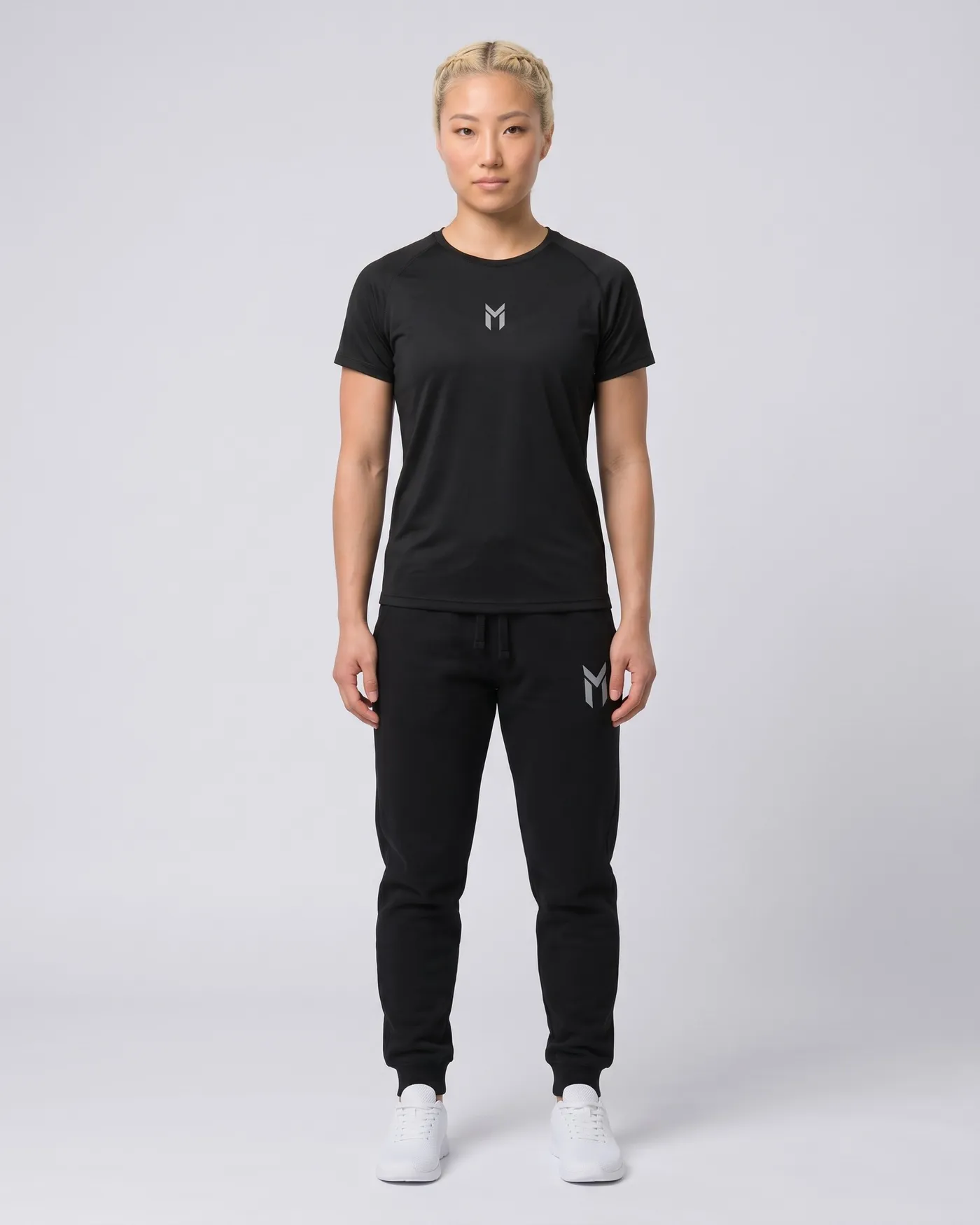 Person in schwarzem Jersey und schwarzen Fleece Joggers vor hellgrauem Grund